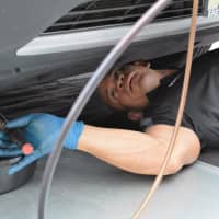 <p>Roberto Gonzalez working under a car on a service road off Route 17 in Rutherford.</p>