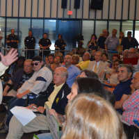 <p>City watchdog John Marshall Lee talks to the crowd at the City Council meeting in Bridgeport Tuesday as David Walker, former U.S Comptroller General (center, holding paper), looks on.</p>