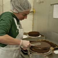 <p>A worker ices a cake.</p>