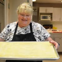 <p>Margaret Klarer of Dumont carrying a tray of baklava ready for the oven.</p>