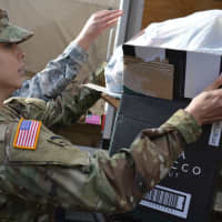 <p>A military member from the Teaneck Armory loads a gift onto a truck.</p>
