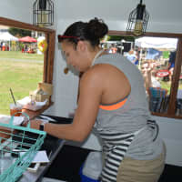 <p>Betsy Arroyo serves a customer at Dixie Doughnuts, a food truck at the Black Rock Farmers Market in Bridgeport.</p>