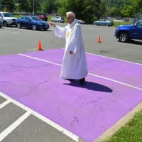 <p>Deacon Richard P. Kovacs sprinkles Holy Water throughout the newest Purple Heart spots at the War Memorial in downtown Danbury.</p>