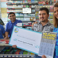 <p>Darwin Aguirre Portillo and Yolanda Vega pose with a giant novelty check following his win of a $2.5 million lottery prize.</p>
