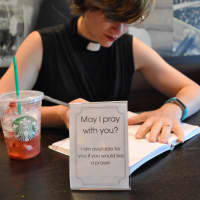 <p>Pastor Jenny McLellan sits in Ramsey Starbucks with her prayer card, an invitation to people to talk.</p>