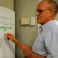 <p>Martin Walker of Ridgewood counts the number of dots on a poster, indicating how much people are concerned about assisting the elderly homebound in the village.</p>