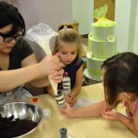 <p>An instructor helps students in the Buttercup Bakery Camp.</p>