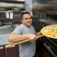 <p>A pizza chef pulls a pie out of the oven at Amalfi Pizzeria and Restaurant.</p>
