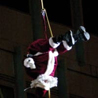 <p>Santa does a backflip as he rappels down Landmark Square.</p>