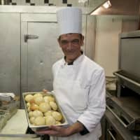 <p>A chef prepares freshly baked rolls at the restaurant.</p>