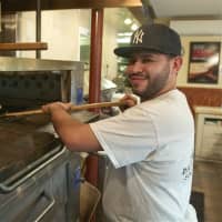 <p>A pizza chef pulls a pie from the oven at Froggy&#x27;s.</p>