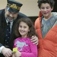 <p>Dennis the Train Man punches a ticket for a child at the Westport Library Thursday.</p>