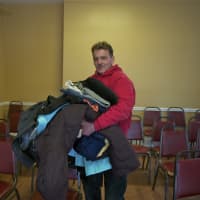 <p>A man brings in donated clothes to be distributed.</p>
