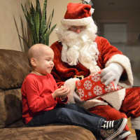 <p>Sitting by Santa, opening presents, Alex Hammer starts to cheer up.</p>