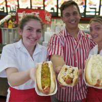 <p>Red Rooster employees show off a few of their popular hot dogs.</p>