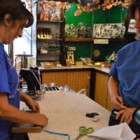 <p>Donna Kattowski, left, wraps a chocolate assortment with a bow for a customer.</p>