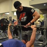 <p>Kahn spots workout partner Craig Behnke of Paramus on bench press with resistance bands, increasing the workload through the negative reps.</p>