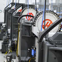 <p>A row of Computer Numerical Control (CNC) machines, each equipped with an array of tools.  A CNC manufactures things. It is programmed to employ each of the tools, as needed, in sequence.</p>