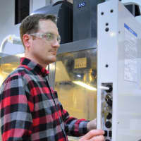 <p>Craig Morgan of Oakland programs a Computer Numerical Control (CNC) machine on a production floor at Triangle Manufacturing.</p>