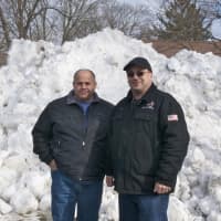 <p>Joe Michelangelo (left) and Joe Palmieri in front of the snow pile loaded into the Snow Melter on Friday in Fairfield.</p>