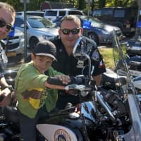 <p>Two Harrison officers pose with a boy on a police motorcycle.</p>