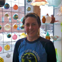 <p>Glass blower Kathleen Andersen in front of some of the store&#x27;s popular glass Christmas ornaments, which students can actually come in and make themselves.</p>
