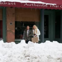 <p>Pedestrians walk behind the snowbanks on Main Street in Beacon.</p>