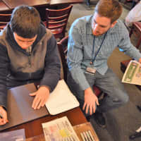 <p>Teacher Assistant Tim Smith of Dumont helps Jonathan Yammerino make a sign.</p>
