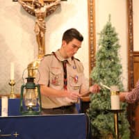 <p>Scout Tim Hahn, at left, helps start the flame lighting at Corpus Christi Church in Hasbrouck Heights Friday night.</p>