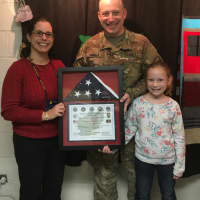 <p>Army Capt. Nicholas J. Minella -- here with his daughter -- presents a flag to Roaring Brook Elementary Principal Amy Fishkin.</p>