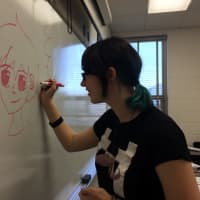 <p>Elmwood Park sophomore Nicole Appel draws an anime style character on the board. </p>