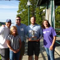 <p>Grace Smith House Executive Director Michele Pollock Rich and Board Chair Barbara Mauri award present the 2015 winners, Michael Davis and Matthew Repp from Meyer Contracting, with the Afternoon of Champions trophy.</p>