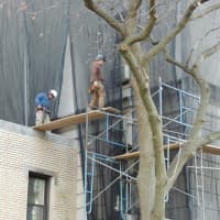<p>Workmen on a scaffolding fastening the mesh in place Friday.</p>