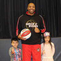 <p>&quot;Big Mike&quot; of the Harlem Wizards poses for a photo with Katonah Elementary School kindergarteners Fidella Swana and Mikey Collindres.</p>