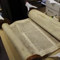 <p>SaNogueira holds a torah from a small village in Poland that was desecrated during the Holocaust.</p>