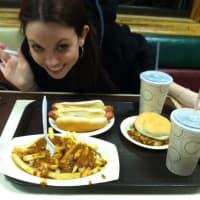 <p>A patron at The Hot Grill in Clifton pauses for a photo opt before chowing down on its Texas hot wieners and fries drenched in gravy.</p>