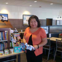 <p>Director of the Free Public Library of Hasbrouck Heights Mimi Hui stands with the 805 donated books by Chick-Fil-A scavenger hunt participants.</p>
