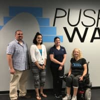 <p>Push to Walk staff Executive Director David Font, Operations Director Stephanie Lajampose, and Program Director Tiffany Warren stand with client Lois Hamilton.</p>