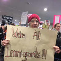<p>Suzy Stark of Monroe keeps her message simple as she joins the protest at Bradley International Airport on Sunday.</p>