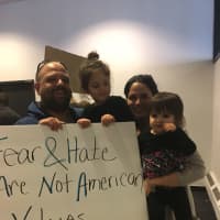 <p>Gina Musumeci of Newtown is joined by her husband and two young daughters at the protest at Bradley International Airport on Sunday.</p>