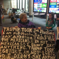 <p>A protester who identified herself only as Shirley joins the crowd at Bradley Airport with her sign propped on her walker. She is 93 and from West Hartford.</p>