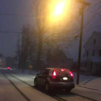 <p>Cars head out at about dawn on Thursday on snow-covered roads in Danbury. A couple of inches of snow are already on the ground.</p>