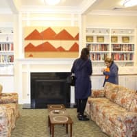 <p>Guests at the ribbon cutting ceremony for Wilton Commons Congregate look over the books shelved in the reception room.</p>