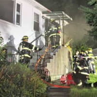 <p>Firefighters head back inside the home as smoke pours from the structure.</p>