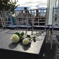 <p>Two white flowers -- which many attendees held -- sit on a granite bench at the memorial Friday morning,.</p>