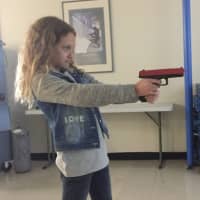 <p>Deanna, 10, uses a fake gun to shoot a target in the force training simulation.</p>