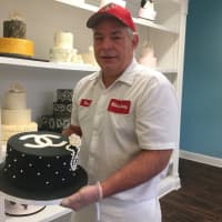 <p>David Miller of Millers Bakery holds a Chanel cake decorated by his wife.</p>