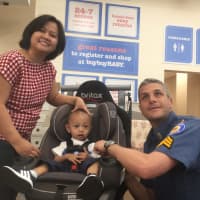 <p>Sergeant Brian Linden and Ana Mallaria fit Lucas into his new car seat.</p>