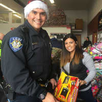 <p>Lodi Police Officer Javier Hernandez and Brianna H. sort through toys at the Closter Fire Department for the annual PBA Toy Drive.</p>