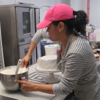 <p>Regina Heredia works on a red velvet cake she will slice up for sale. Cindy Capitani</p>